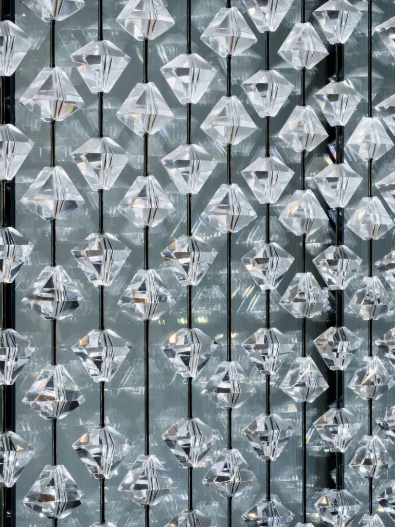 Interior application featuring faceted diamond-like crystal modules and hanging geometric elements; diamond crystal partition interior application 003 with vertical suspension strands and repeated modular spacing.